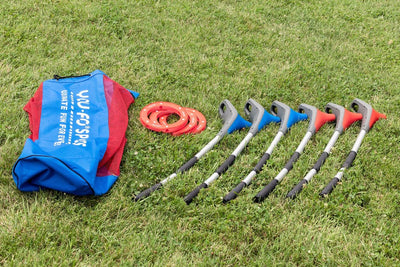 Blue and red YOUFO group game sticks lined up, laying in the grass next to three red game rings and a red and blue YOUFO carrying bag. 