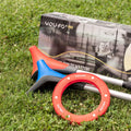 Red and blue YOUFO game sticks, red ring, and box on grass. 