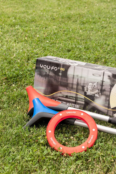 Red and blue YOUFO game sticks, red ring, and box on grass. 
